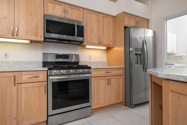 kitchen featuring appliances with stainless steel finishes, light tile patterned floors, light stone countertops, and light brown cabinets