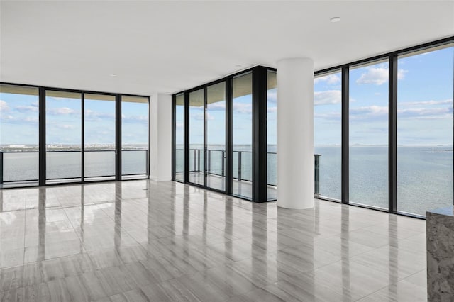 unfurnished room with a wall of windows and a water view