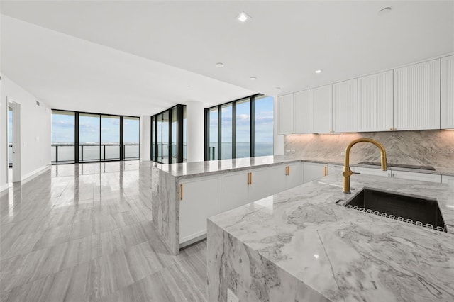 kitchen featuring floor to ceiling windows, light stone countertops, a healthy amount of sunlight, and white cabinets