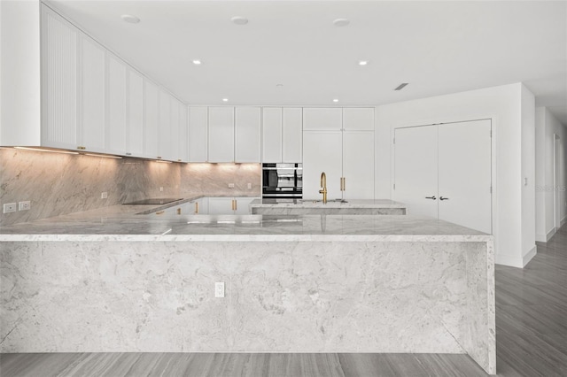 kitchen featuring sink, white cabinetry, black appliances, light stone countertops, and backsplash