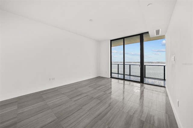 unfurnished room featuring expansive windows and a water view