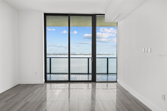 spare room with floor to ceiling windows and a water view