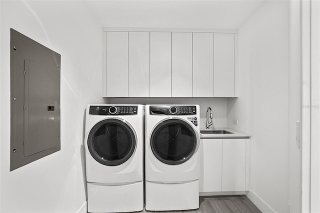 laundry area featuring sink, electric panel, cabinets, separate washer and dryer, and light wood-type flooring