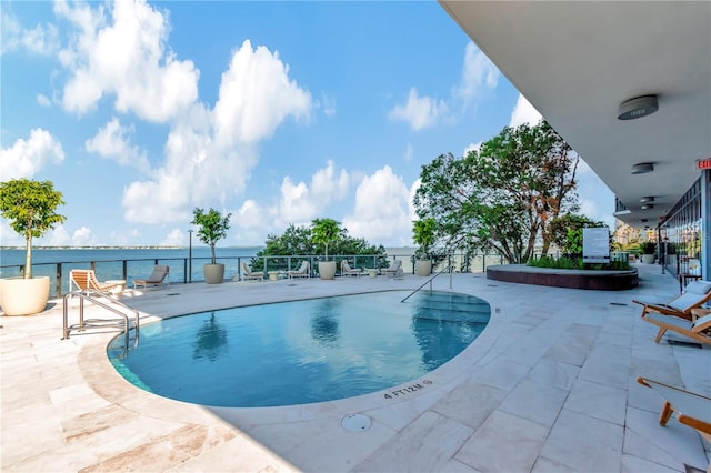 view of swimming pool with a water view and a patio area