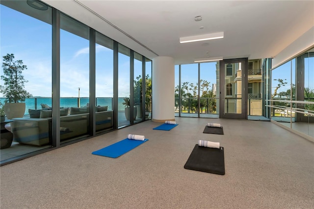 exercise room featuring a water view and floor to ceiling windows