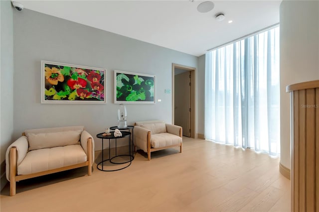 sitting room with hardwood / wood-style floors and expansive windows