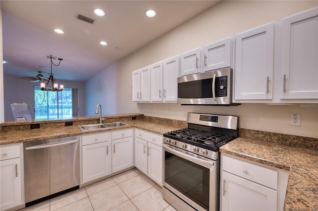 kitchen featuring white cabinetry, stainless steel appliances, decorative light fixtures, and sink