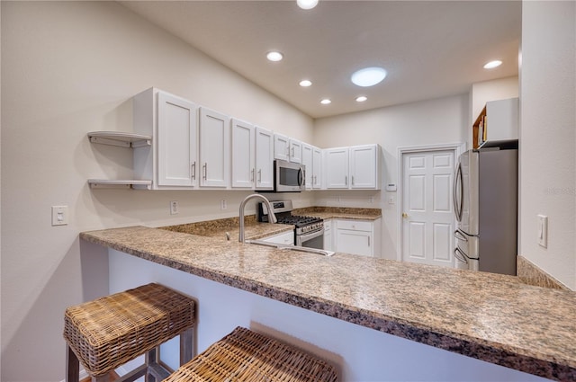 kitchen with appliances with stainless steel finishes, a breakfast bar, white cabinets, and kitchen peninsula