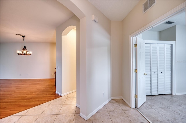 hallway featuring light tile patterned flooring and an inviting chandelier