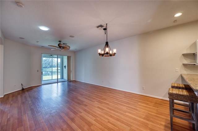 unfurnished room with ceiling fan with notable chandelier and light hardwood / wood-style floors