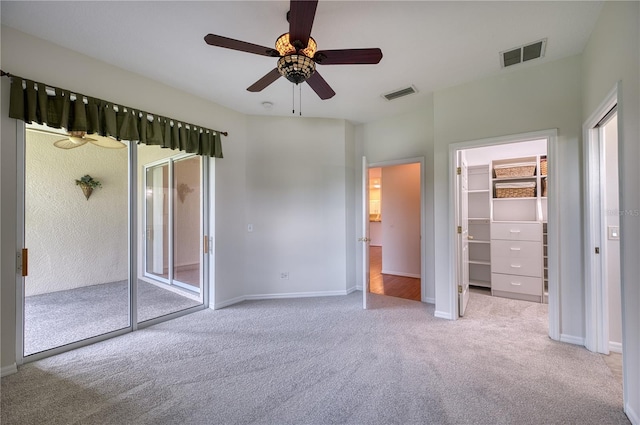 unfurnished bedroom featuring a spacious closet, access to exterior, ceiling fan, light carpet, and a closet