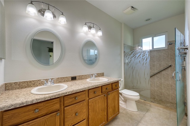 bathroom with vanity, a tile shower, tile patterned floors, and toilet