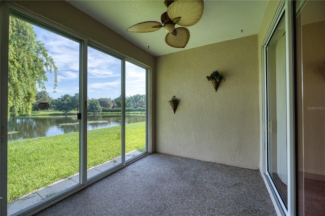 unfurnished sunroom featuring a water view and ceiling fan