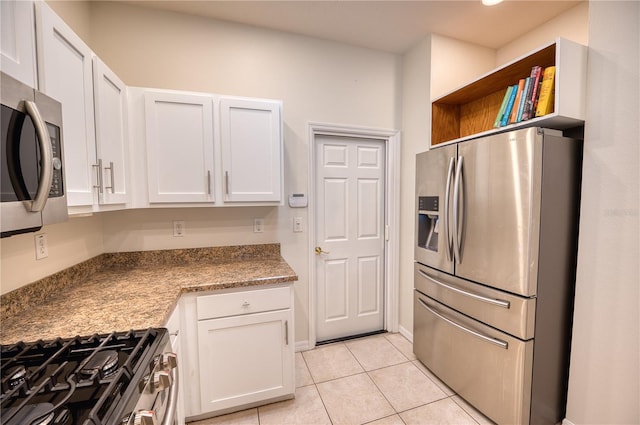 kitchen with light tile patterned floors, stainless steel appliances, white cabinets, and stone counters