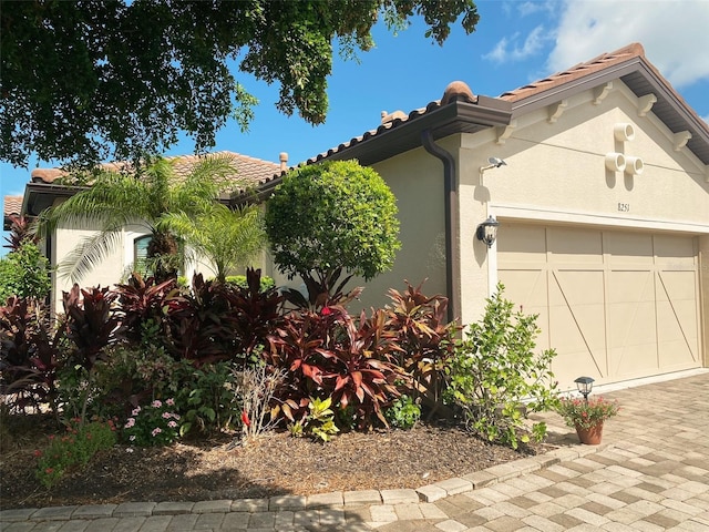 view of front facade featuring a garage, a tiled roof, and stucco siding