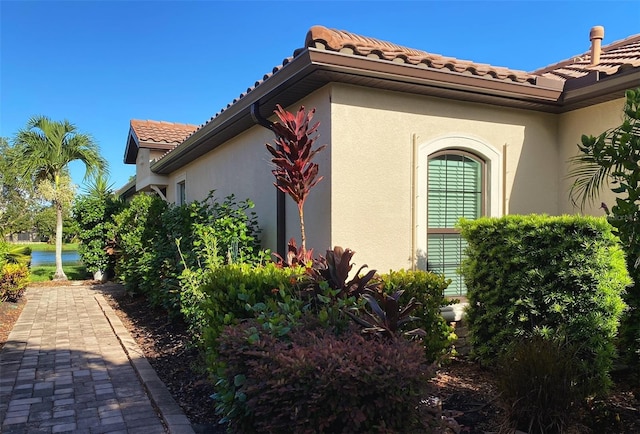 view of side of home with a tile roof and stucco siding