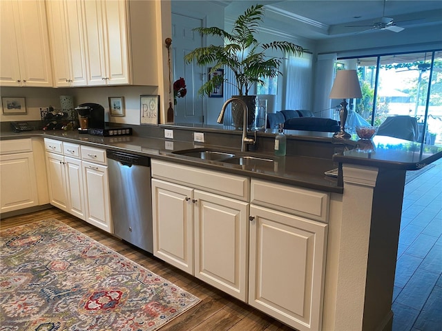 kitchen with dishwasher, dark countertops, open floor plan, a peninsula, and a sink