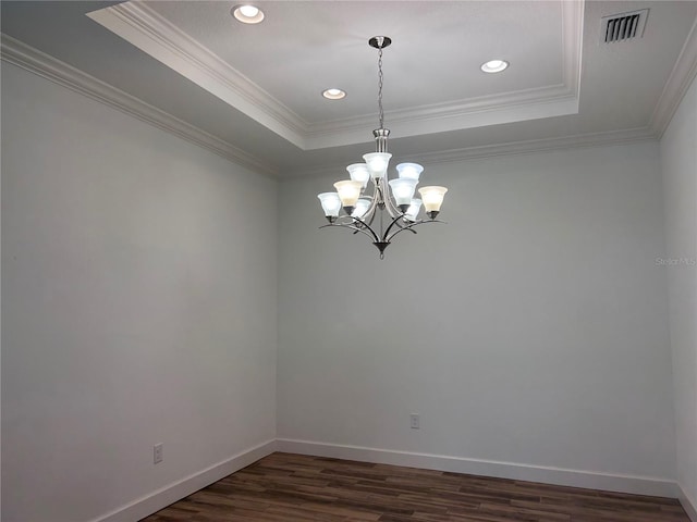 spare room featuring dark wood-style floors, a raised ceiling, and baseboards