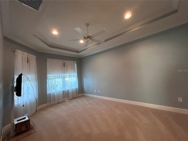 empty room featuring a raised ceiling, visible vents, ornamental molding, light carpet, and baseboards