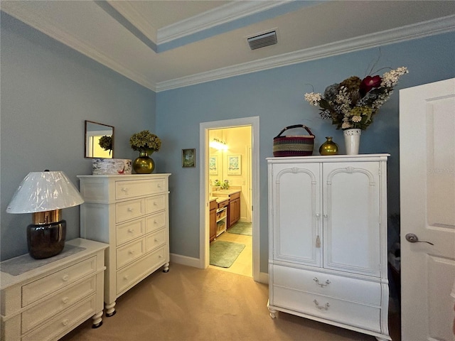 bedroom featuring visible vents, baseboards, ornamental molding, a raised ceiling, and ensuite bath