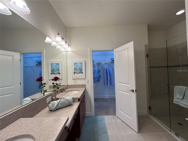 bathroom with a stall shower, tile patterned floors, a sink, and double vanity