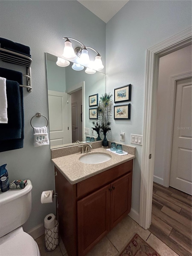 half bath featuring toilet, wood finished floors, and vanity