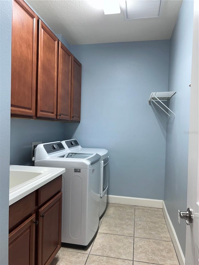 washroom with cabinet space, light tile patterned flooring, baseboards, and washing machine and clothes dryer