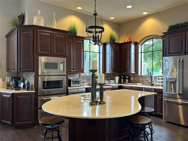 kitchen with dark wood-style floors, a breakfast bar area, stainless steel appliances, dark brown cabinets, and light countertops