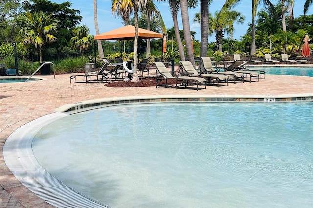 community pool with a patio area, fence, and a gazebo