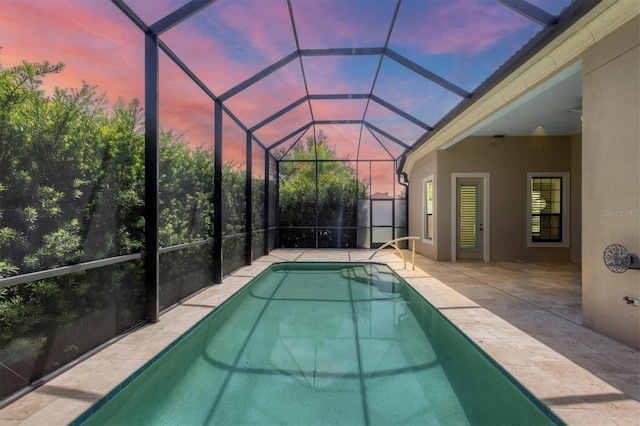 pool at dusk featuring a lanai and a patio area