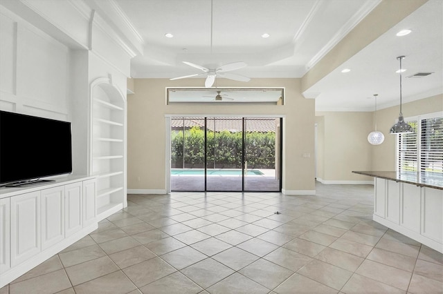 unfurnished living room with a tray ceiling, ornamental molding, built in features, and light tile patterned flooring