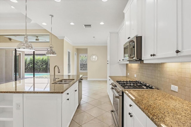 kitchen with sink, stone counters, stainless steel appliances, white cabinets, and a center island with sink