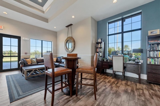 dining space featuring a towering ceiling and wood-type flooring