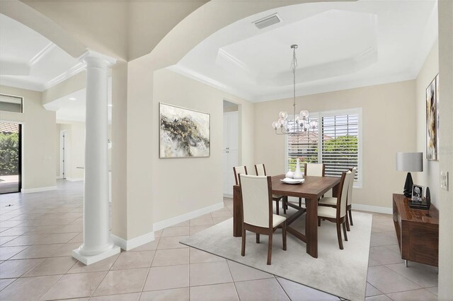 tiled dining area featuring ornamental molding, decorative columns, a raised ceiling, and a chandelier