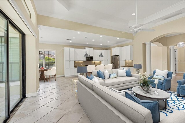 tiled living room featuring decorative columns, crown molding, and ceiling fan