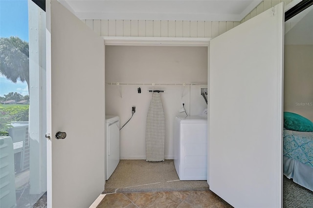 laundry area featuring tile patterned floors, washer and clothes dryer, and a wealth of natural light