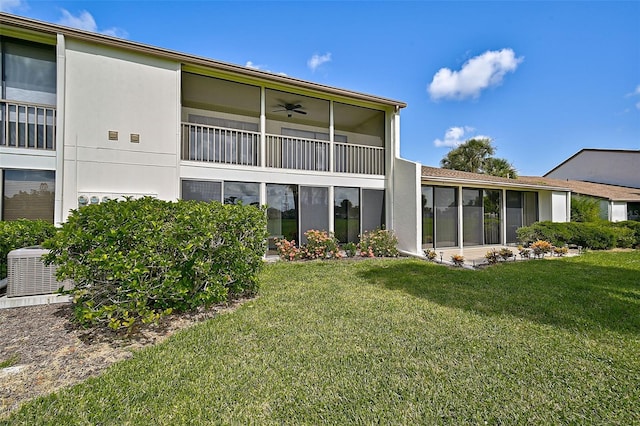 back of property featuring a yard, a balcony, ceiling fan, and central air condition unit