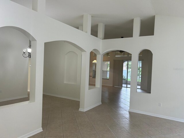 unfurnished room with tile patterned flooring and a towering ceiling