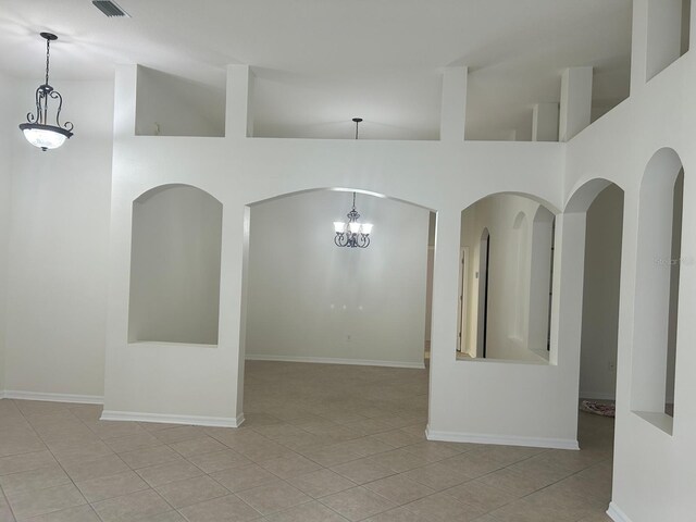 tiled empty room with an inviting chandelier and high vaulted ceiling