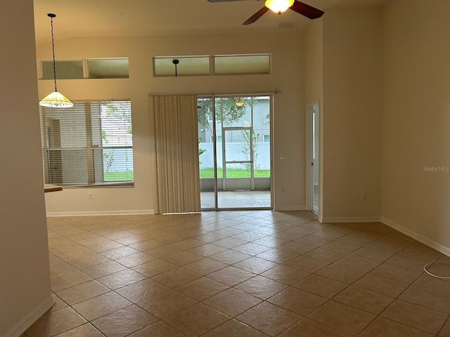 spare room featuring a healthy amount of sunlight, a towering ceiling, light tile patterned floors, and ceiling fan