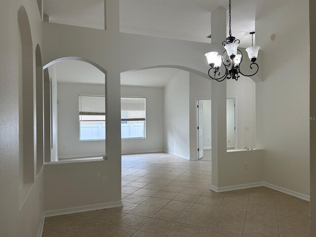 empty room featuring a notable chandelier and light tile patterned floors