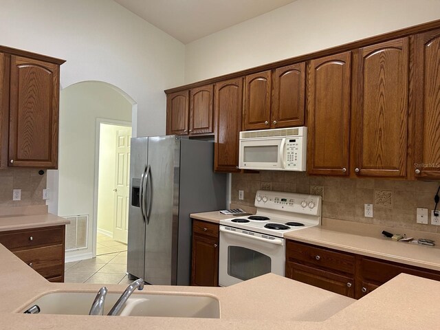 kitchen featuring sink, light tile patterned floors, tasteful backsplash, and white appliances