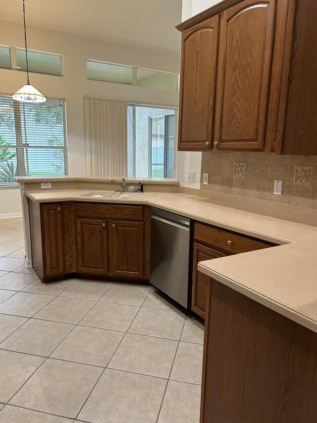 kitchen with light tile patterned flooring, dishwasher, tasteful backsplash, and hanging light fixtures