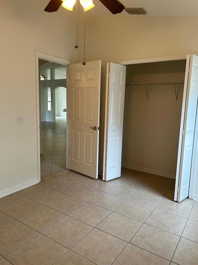 unfurnished bedroom featuring ceiling fan, light tile patterned floors, and a closet