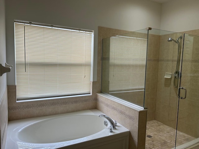 bathroom featuring independent shower and bath and a healthy amount of sunlight