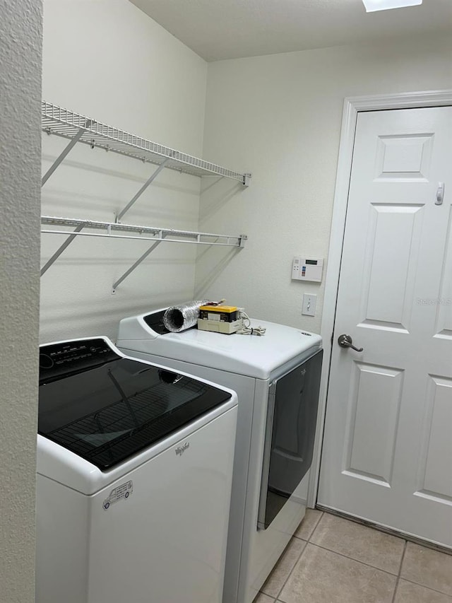 washroom featuring washer and clothes dryer and light tile patterned floors