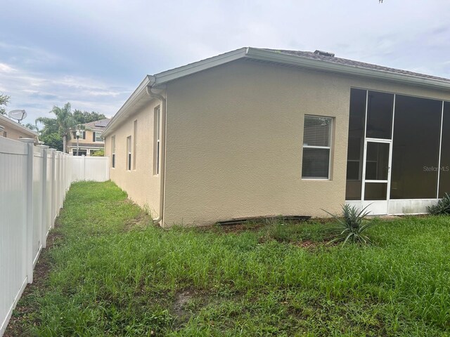 view of side of property with a sunroom and a yard