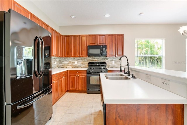 kitchen with light tile patterned floors, decorative backsplash, a notable chandelier, black appliances, and sink