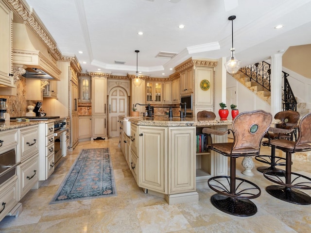 kitchen with light stone countertops, backsplash, a raised ceiling, and hanging light fixtures