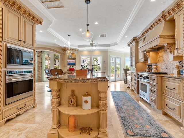 kitchen featuring french doors, stainless steel appliances, a raised ceiling, pendant lighting, and a center island